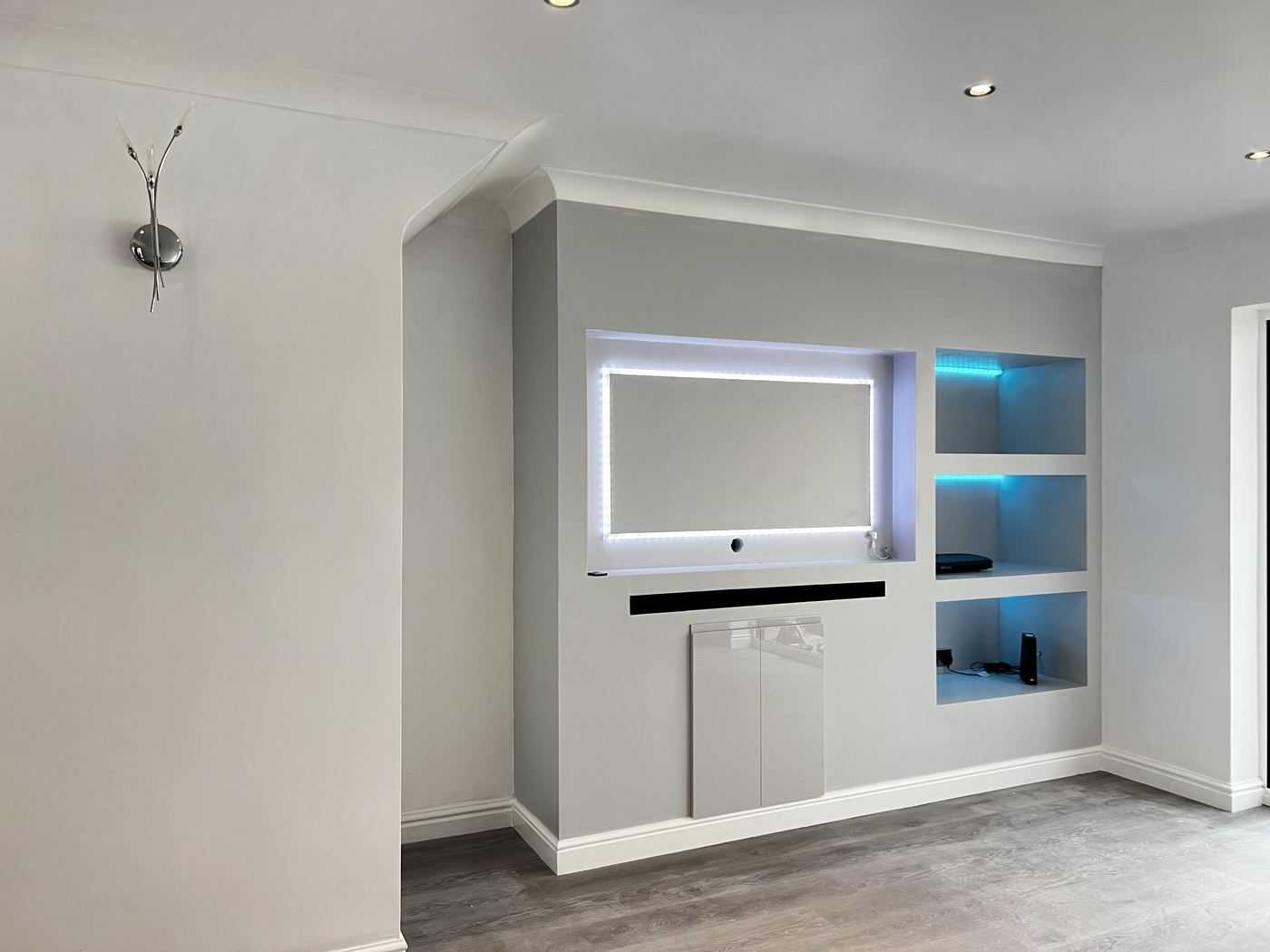 Living room media wall with recessed LED-lit shelving and fresh coving